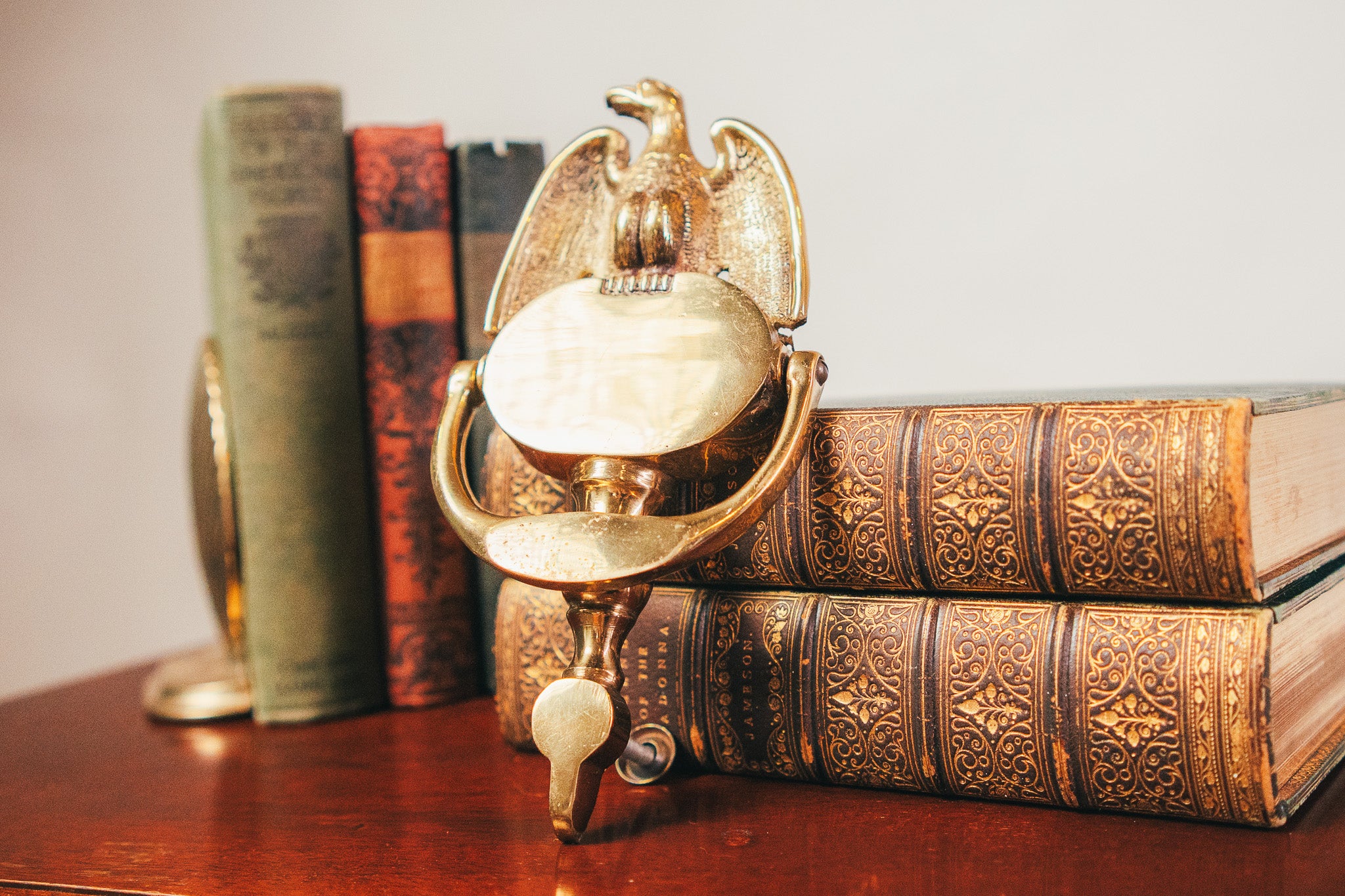 Decorative brass globe on top of vintage books with a blurred bookshelf in the background.