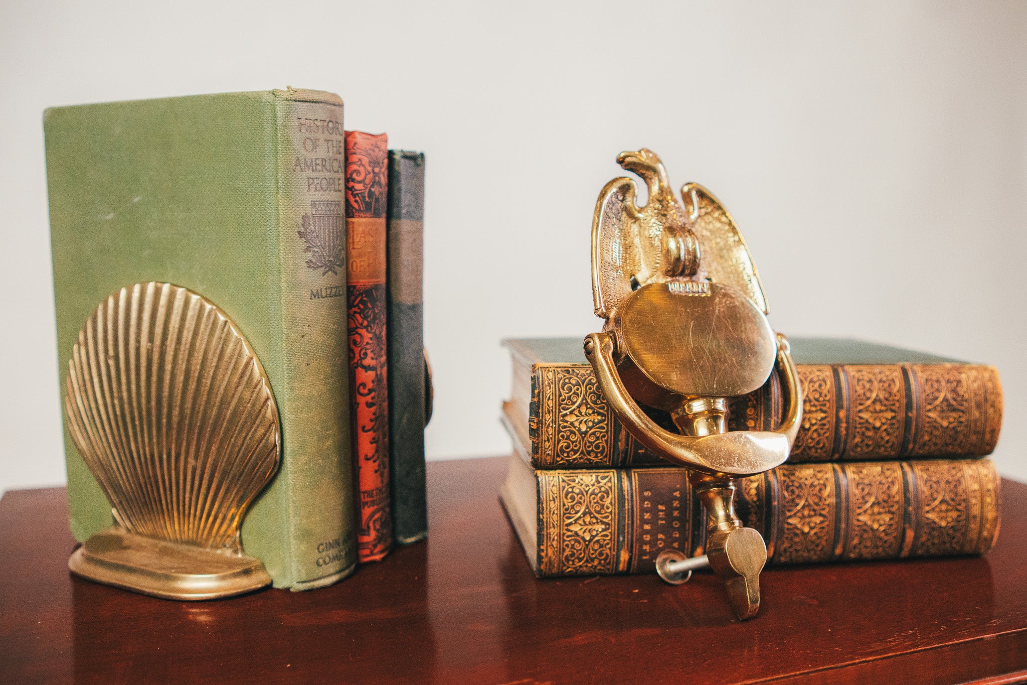 Decorative bookends shaped like a shell and a seahorse on top of vintage books.
