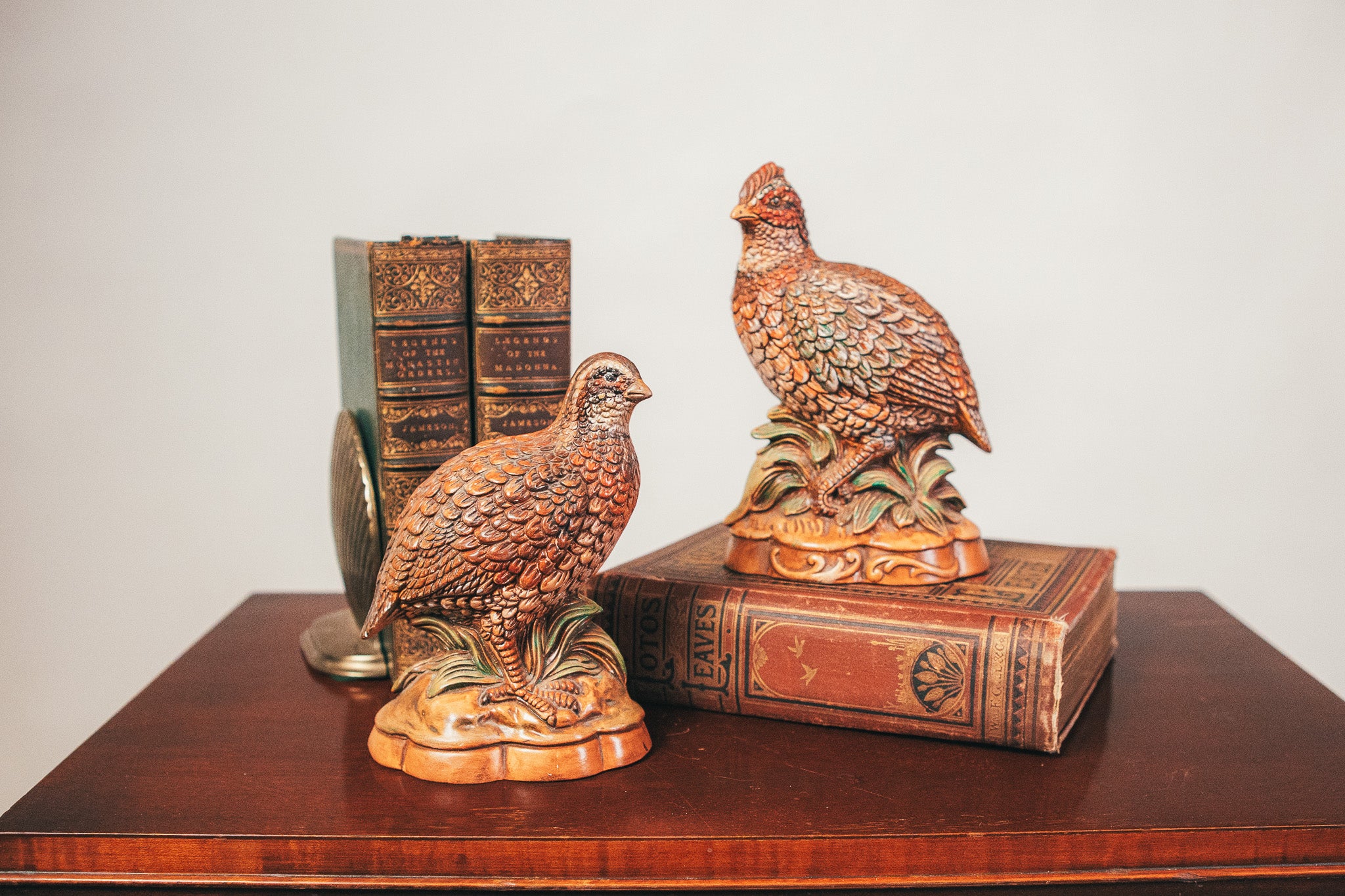 Decorative bird statues on books with a plain background