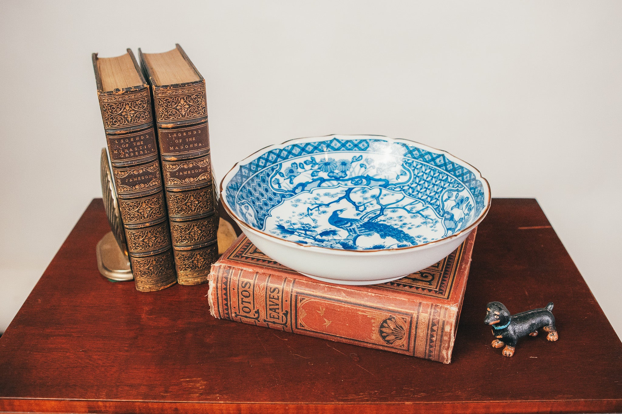 Blue and white ceramic bowl on vintage books with a small figurine on a wooden surface