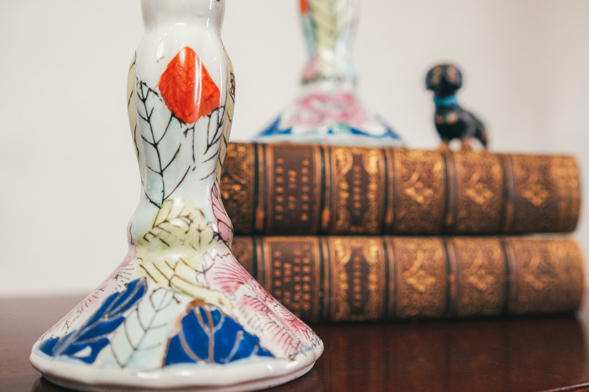 Decorative ceramic piece with colorful patterns on a wooden surface with books in the background.