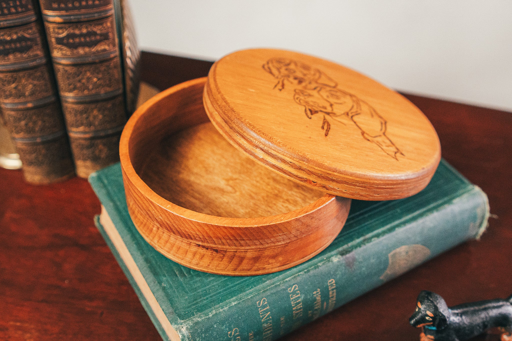 Wooden box with lid on top of a book