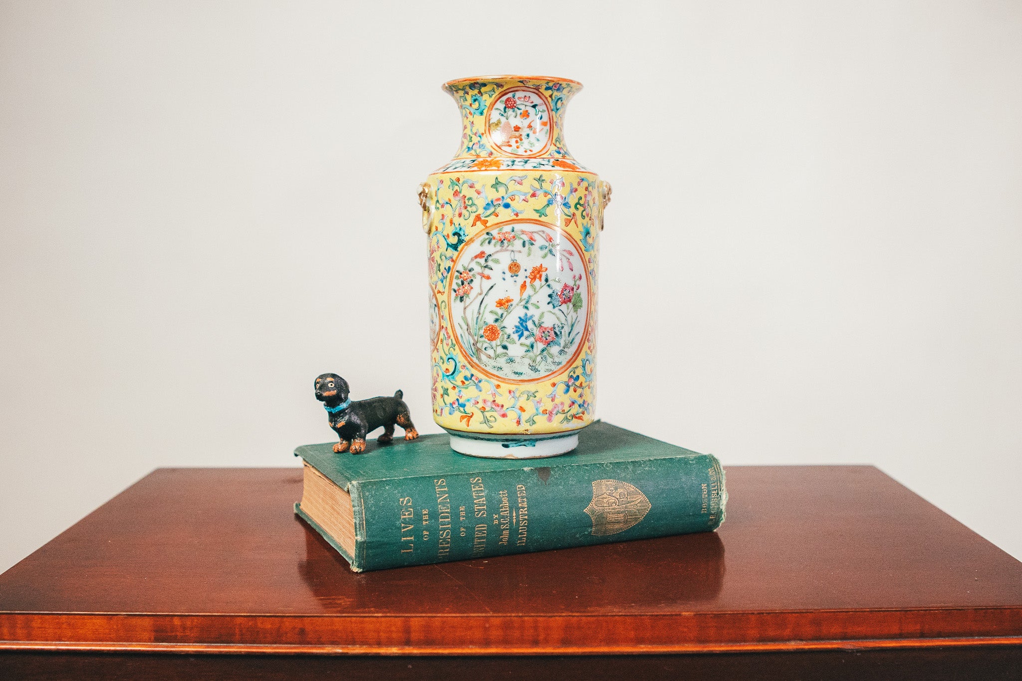 Decorative vase with floral patterns on a book on a wooden surface