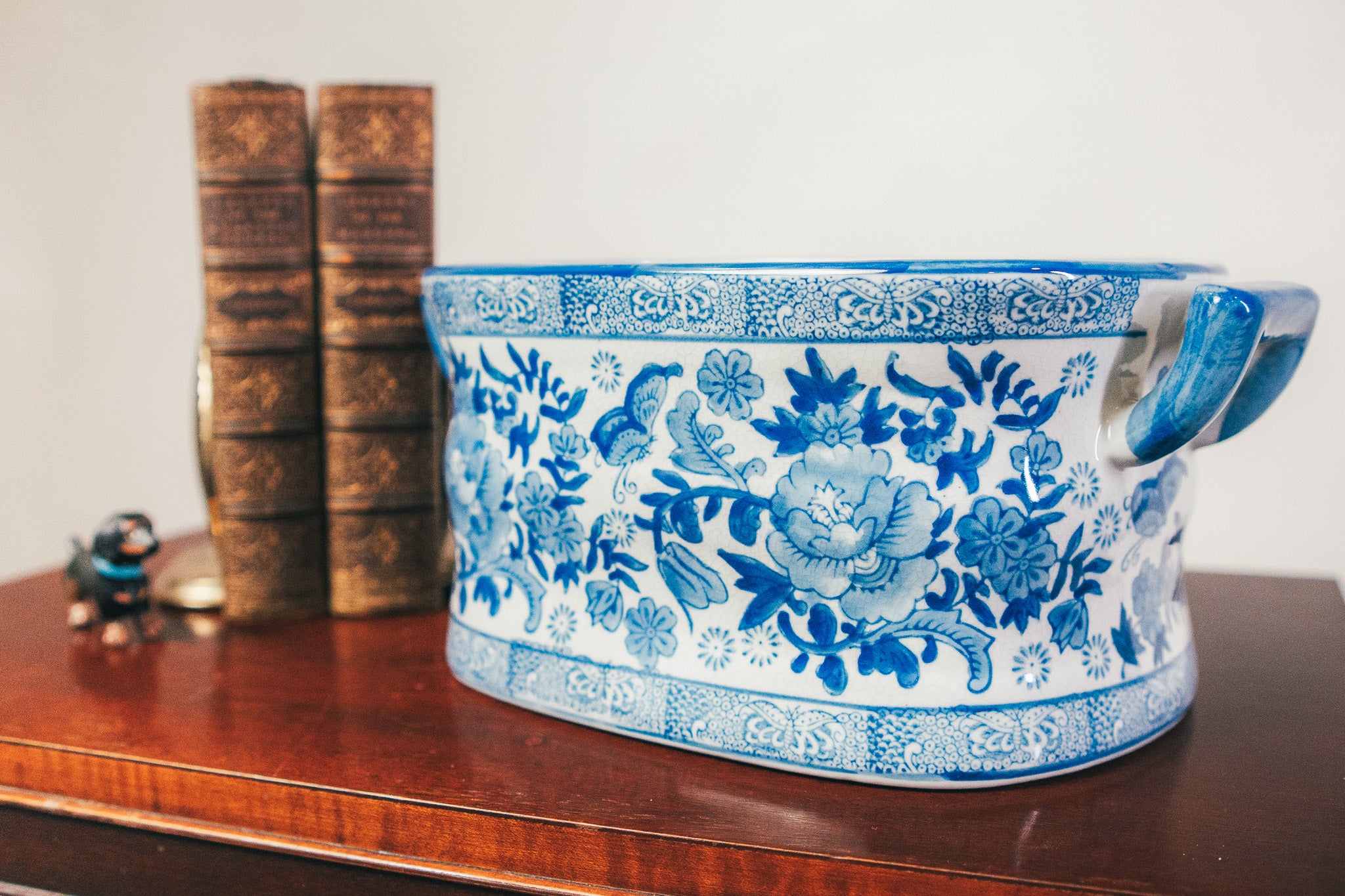 Blue and white floral-patterned ceramic bowl on a wooden surface with books in the background.
