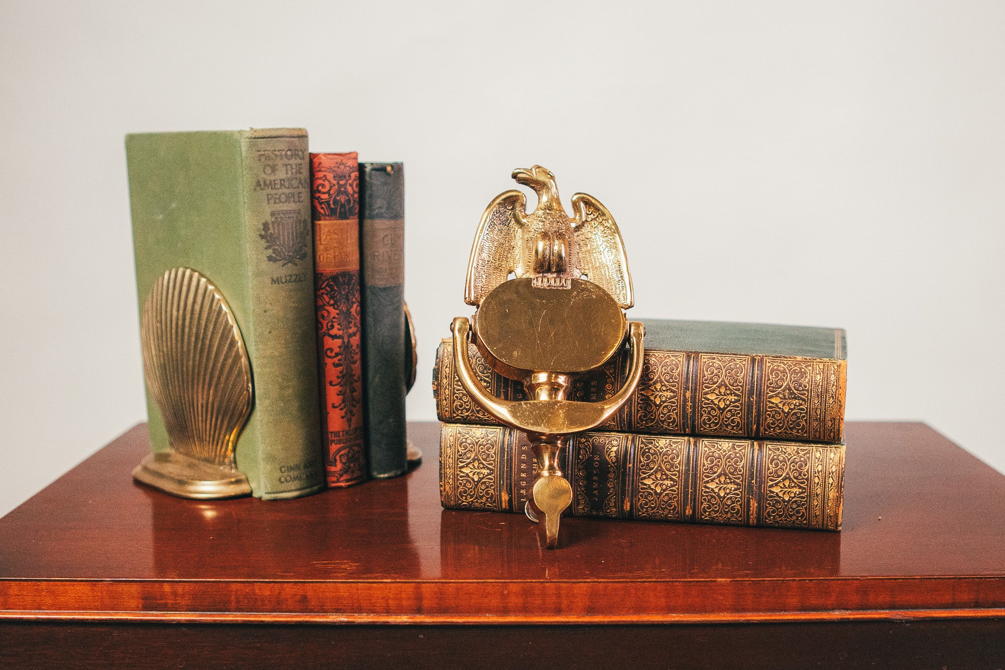 Decorative bookends with a gold eagle design on top of vintage books on a wooden surface.