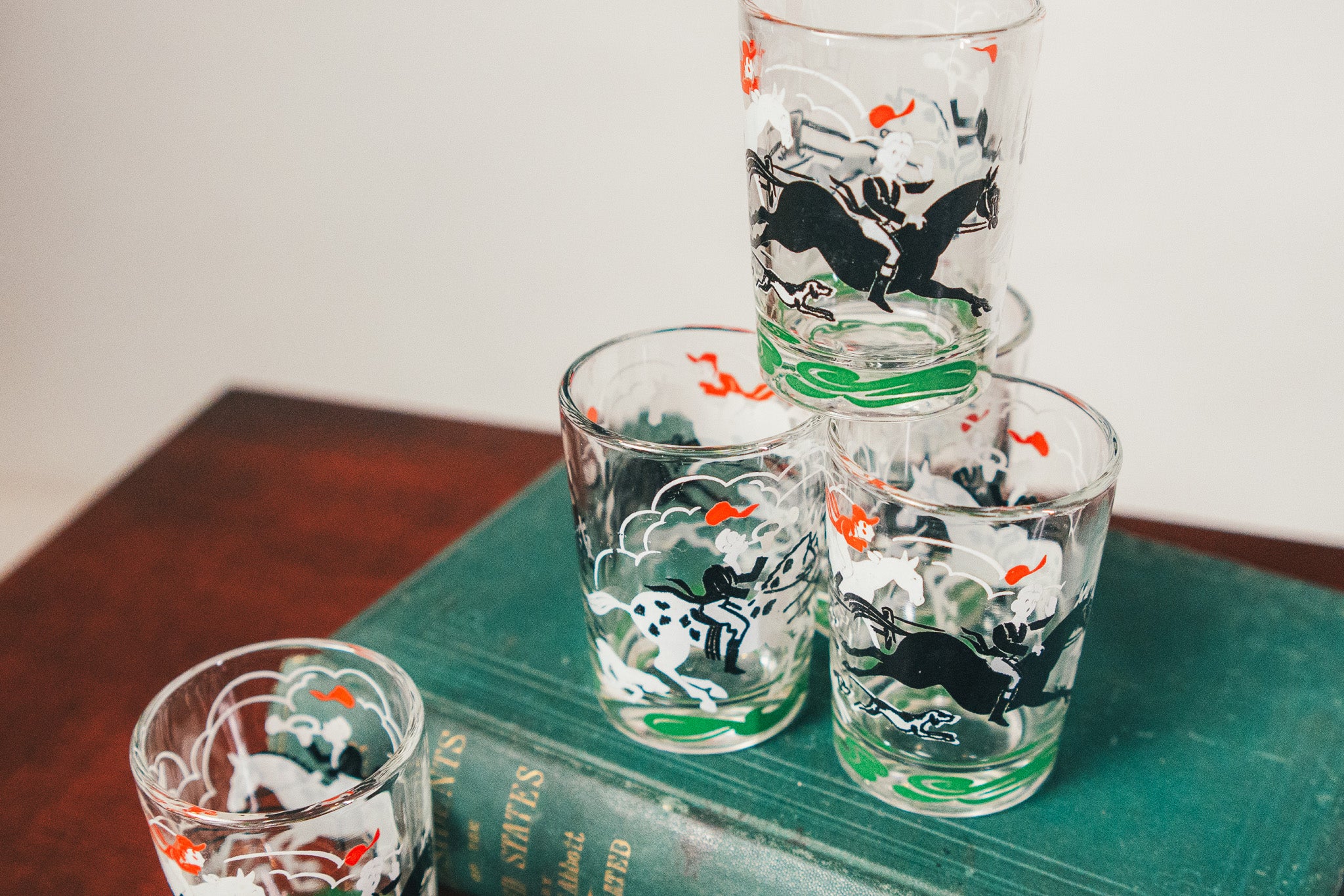 Set of shot glasses with cow design on a green book
