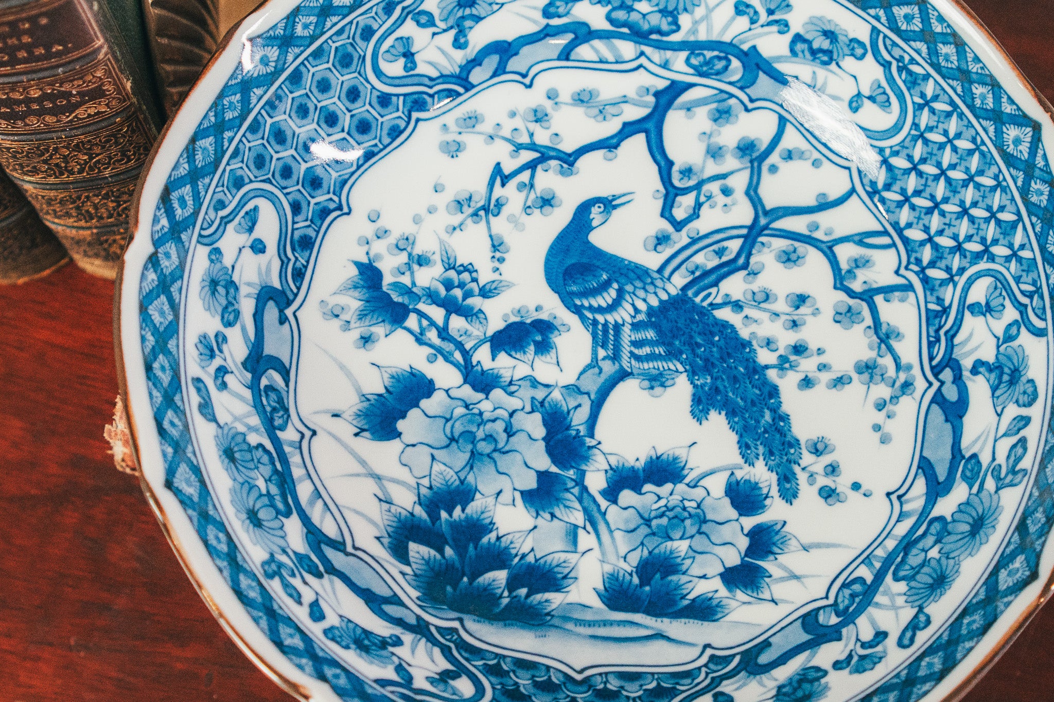 Blue and white ceramic plate with peacock design on a wooden surface