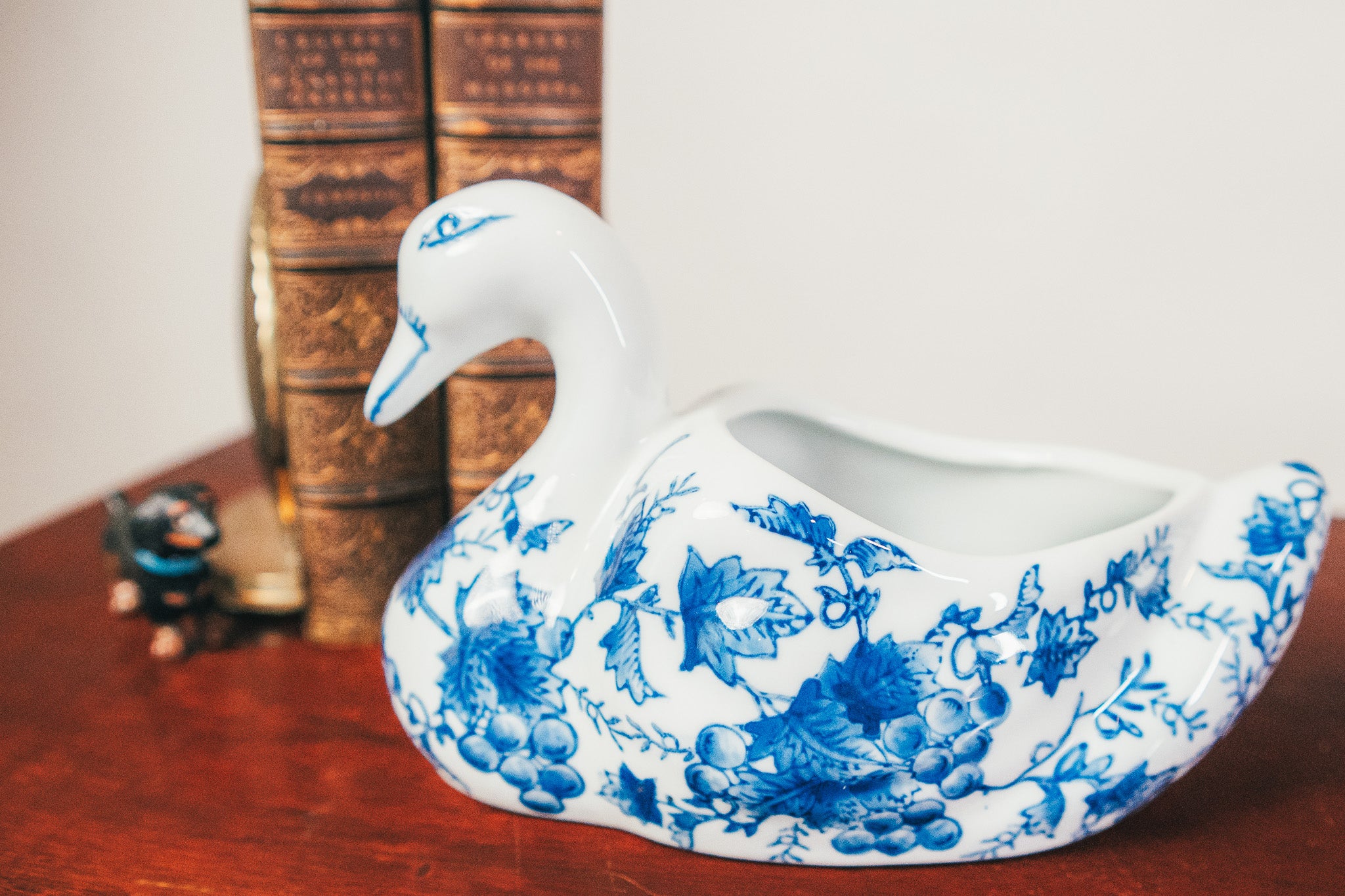 Decorative swan-shaped vase with blue floral patterns on a wooden surface.