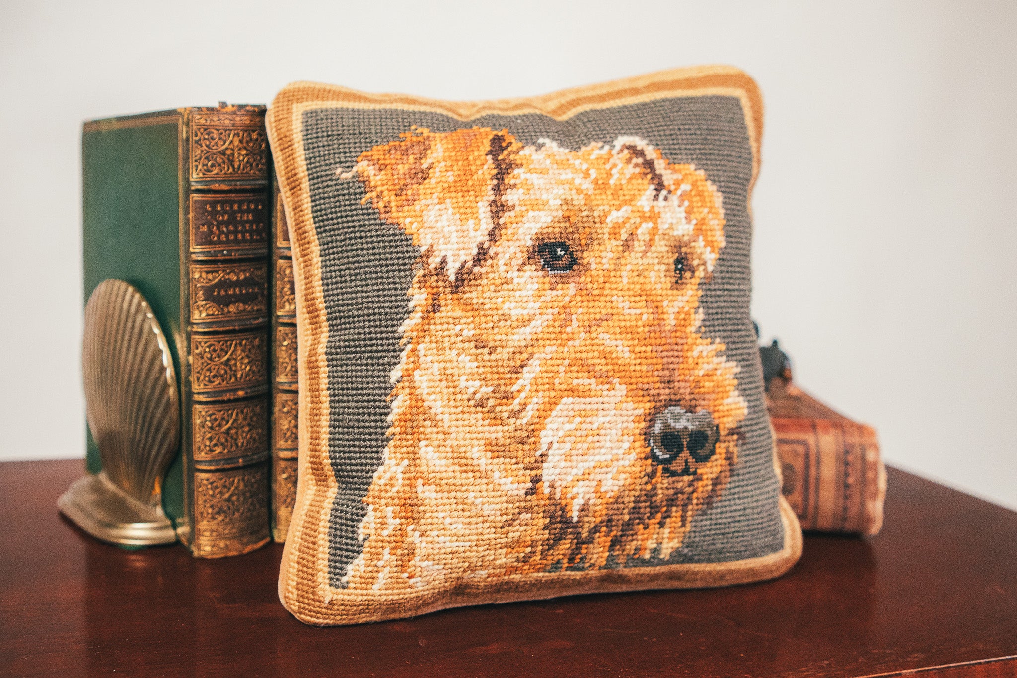 Decorative pillow with a dog design on a wooden surface next to a book