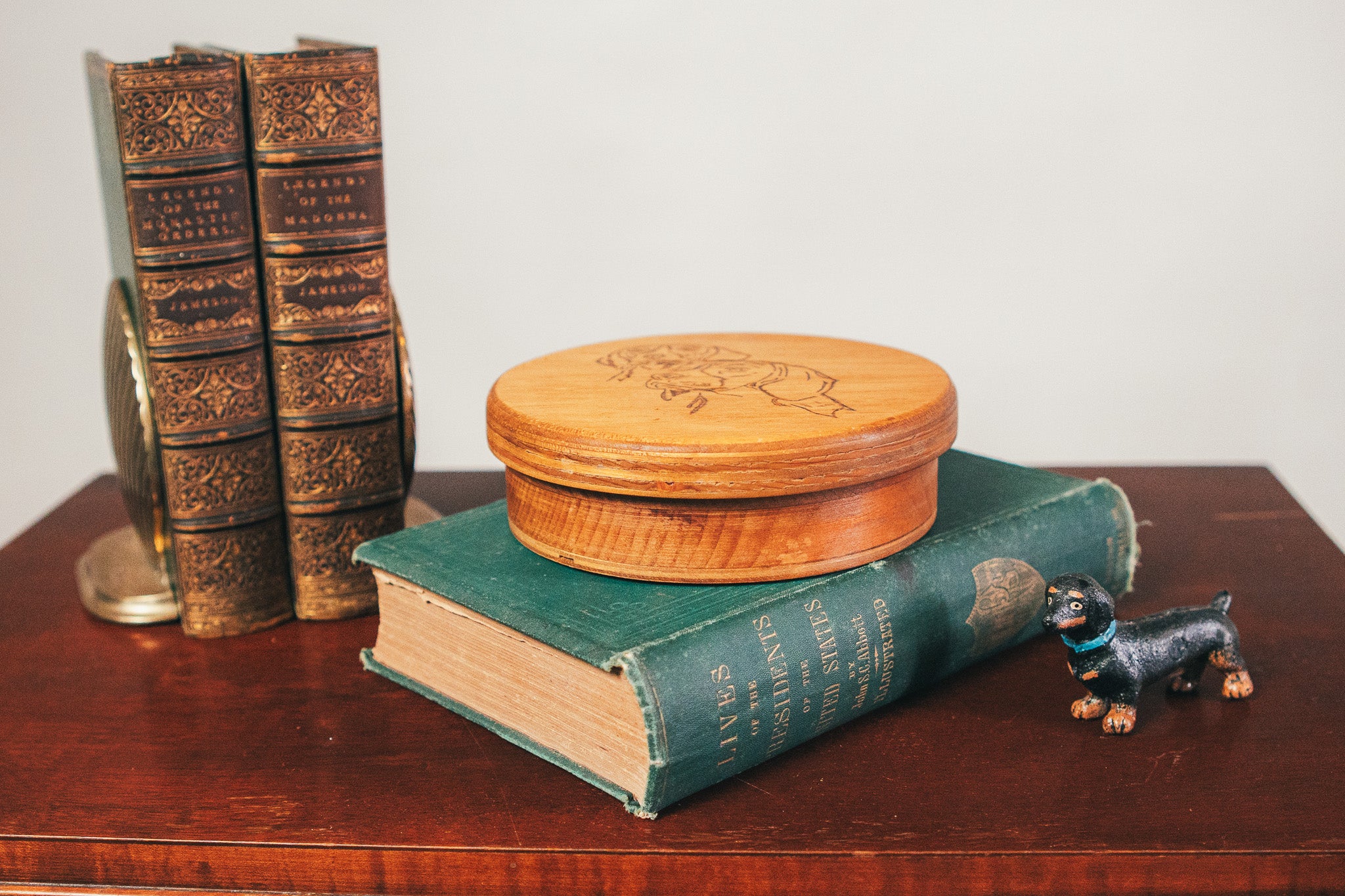 Wooden box on a book with a small figurine of a dog on a wooden surface